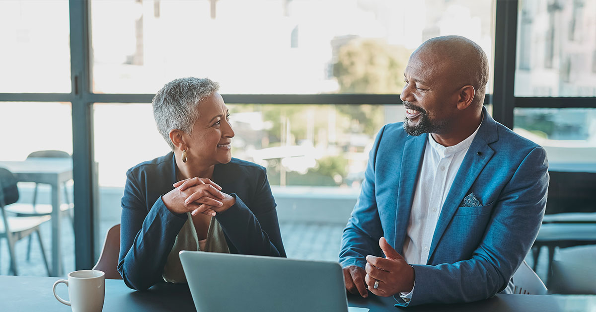 a man and a woman sitting at a table using a laptop